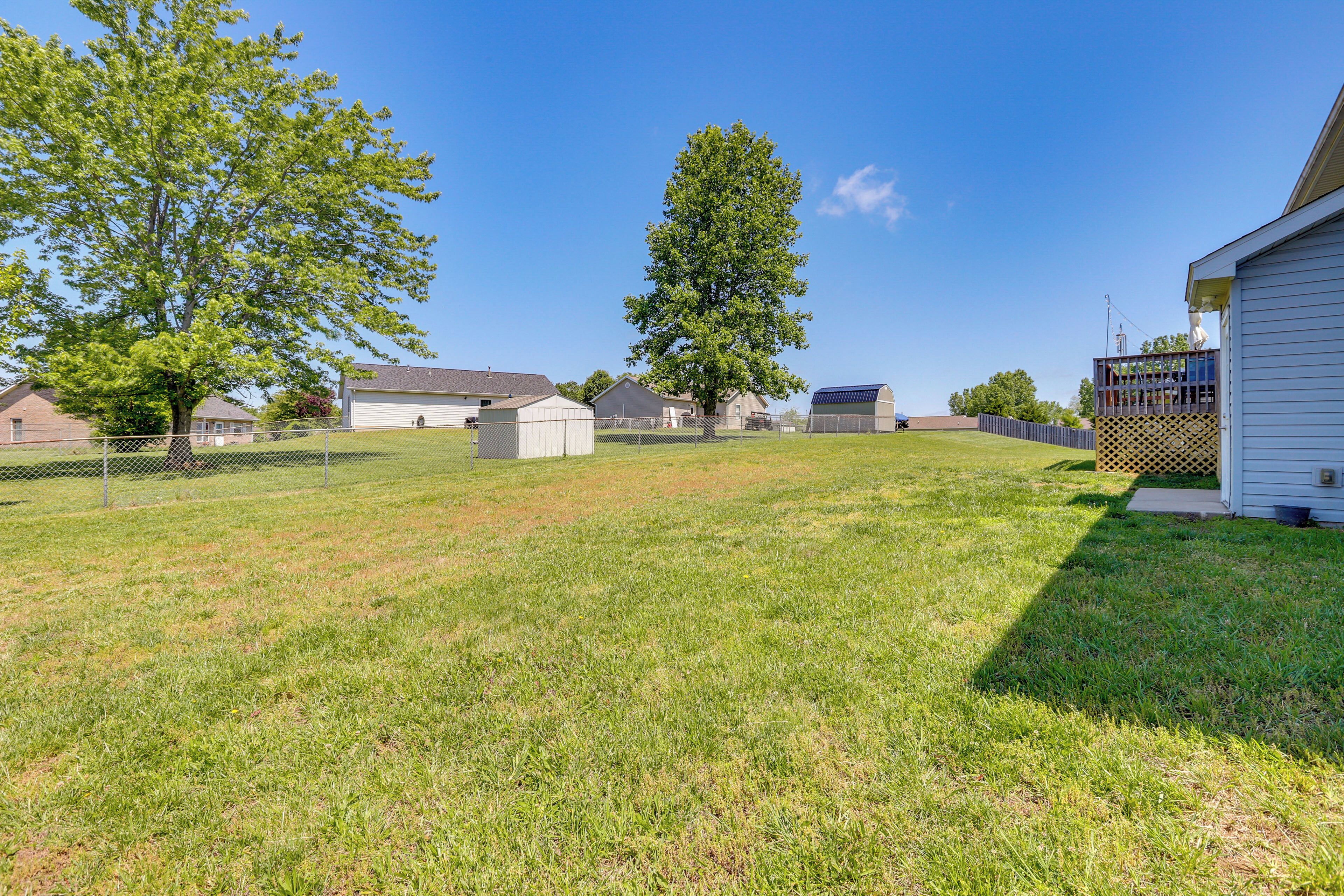 A residential area with a fenced yard, a large tree, and a house with a garage.