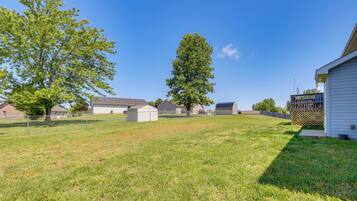 A residential area with a fenced yard, a large tree, and a house with a garage.