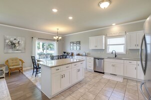 Una cocina moderna con armarios blancos, una isla central y un refrigerador de acero inoxidable.