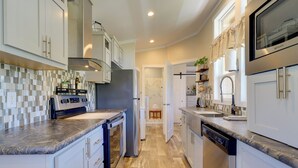 A modern kitchen with white cabinetry, a marble countertop, stainless steel appliances, and a wooden floor. - Chiricahua Birding Cabin By Cave Creek Canyon! (San Simon)