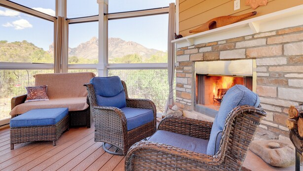 A cozy outdoor seating area with wicker furniture, a stone fireplace, and a view of mountains. - Chiricahua Birding Cabin By Cave Creek Canyon! (San Simon)