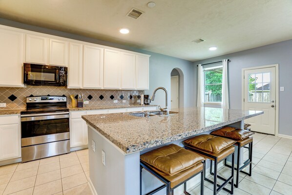 A kitchen with white cabinets, a stainless steel oven, a granite countertop, and a sink. - Private Yard & Furnished Patio! Rosenberg Retreat (Richmond)