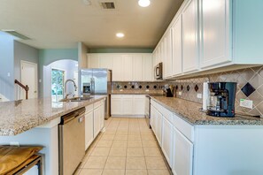 A kitchen with white cabinets, a granite countertop, and a coffee maker.