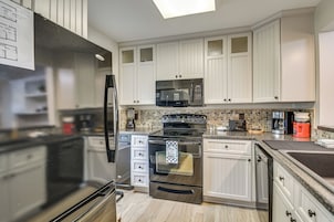Una cocina moderna con electrodomésticos de acero inoxidable, armarios blancos y salpicadero de azulejos.