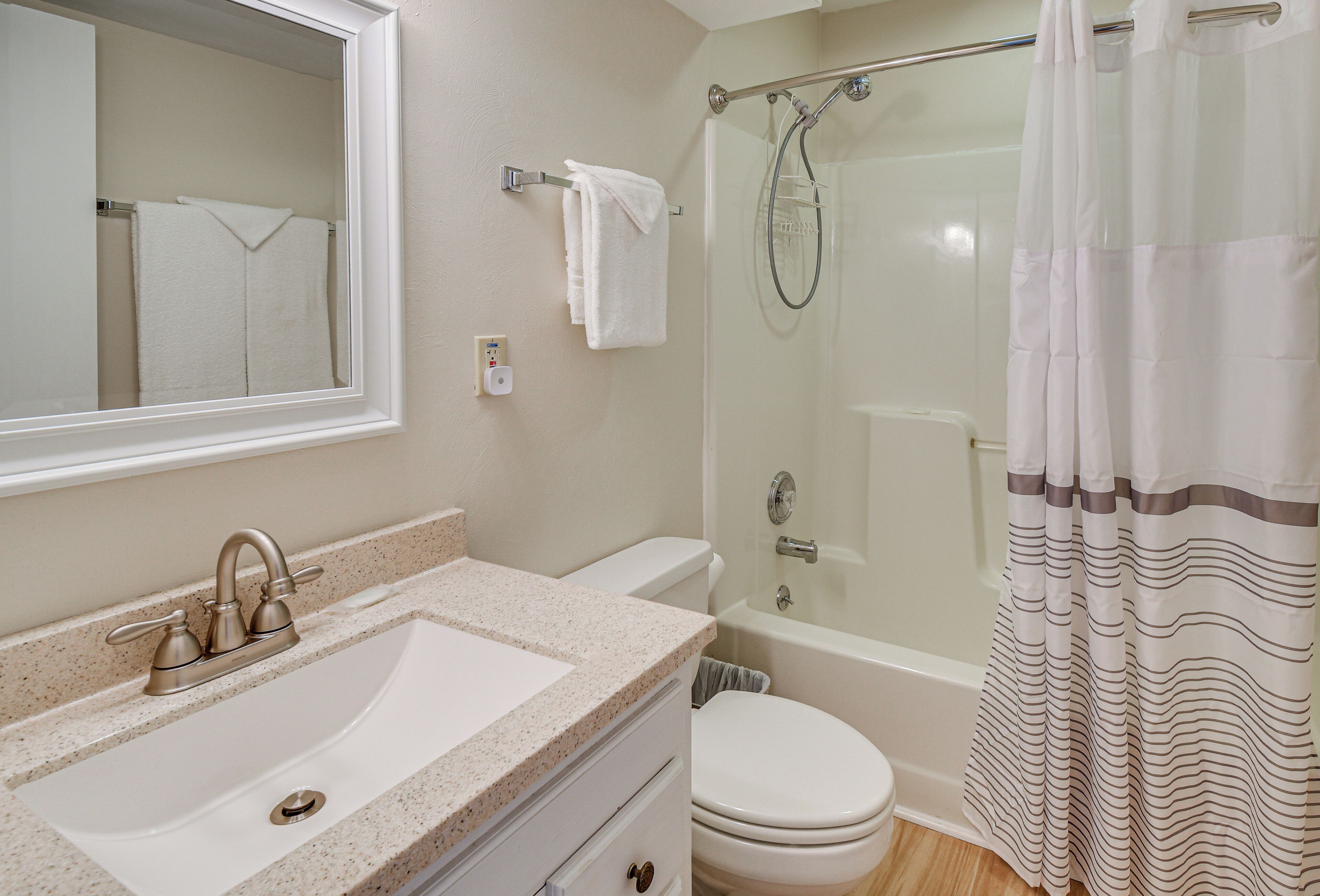 A bathroom with a sink, toilet, shower, and a mirror.