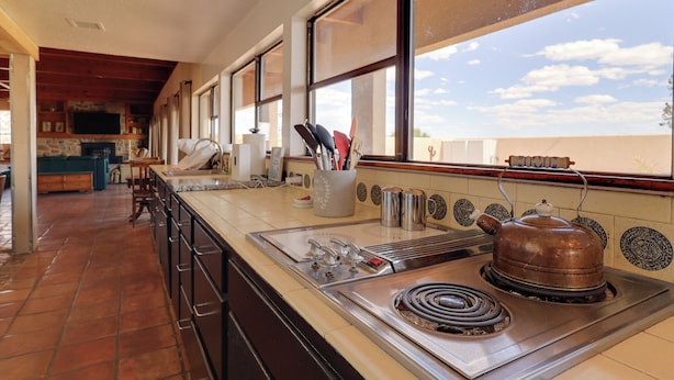 A kitchen with a stove, sink, and large windows.