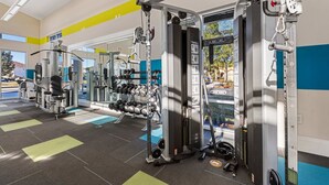 Un gimnasio con equipo de ejercicio, espejos y vistas al exterior.