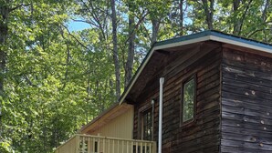 A cabin with a wooden deck and a stone foundation.