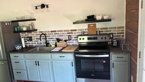 A kitchen with a brick backsplash, stainless steel appliances, and light blue cabinetry.