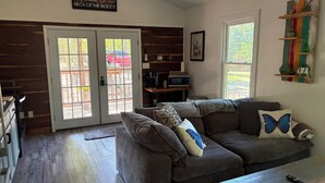 A living room with a brown couch, a coffee table, a fireplace, and a large window.