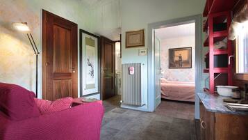 Een kamer met een houten deur, een radiator, een roze stoel en een bed met bloemenbehang.