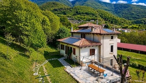 A two-story building with a tiled roof, solar panels, and a patio with outdoor seating.