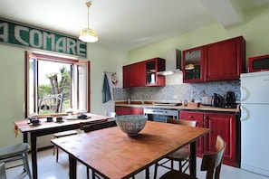 Una cucina con pensili rossi, un fornello e un'area pranzo con tavolo e sedie.