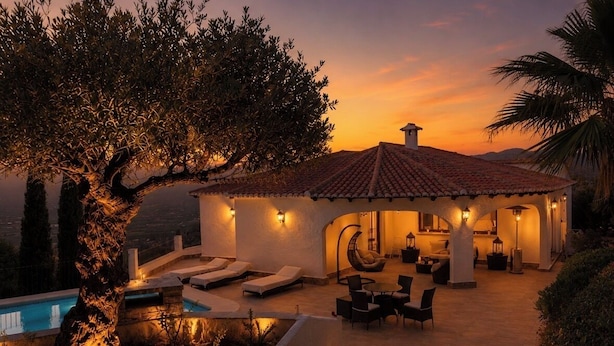 Een villa met zwembad, terras en uitzicht op de ondergaande zon.