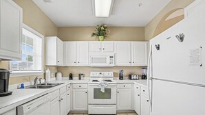 A kitchen with white cabinets, a microwave, stove, and refrigerator. - Ironwood #1433 New on Program! Great Location and Lots of Amenities! (North Myrtle Beach)