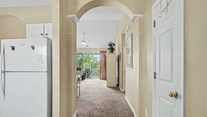 A hallway with a refrigerator, a ceiling fan, and a door leading to a balcony. - Ironwood #1433 New on Program! Great Location and Lots of Amenities! (North Myrtle Beach)