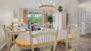 A dining area with a chandelier, wooden chairs, a table, and a view of the outdoors. - Ironwood #1433 New on Program! Great Location and Lots of Amenities! (North Myrtle Beach)