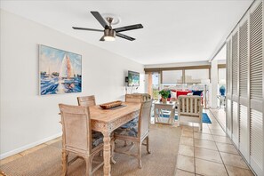 A dining area with a wooden table and chairs, a ceiling fan, and a painting of sailboats on the wall. - Gulfstream Condos Unit 321 | Pool & Hot Tub | Private Balcony Gulf View (Corpus Christi)