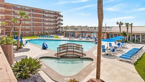 Et hotel med swimmingpool, liggestole og palmer.