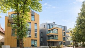 A modern building with a mix of wooden and metal facades, large windows, and a paved courtyard with benches. - Love Story Studio with Jacuzzi Sopot (Sopot)
