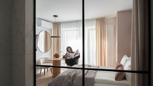 A hotel room with a bed, a desk, a chair, a round mirror, and a window with curtains. - Love Story Studio with Jacuzzi Sopot (Sopot)