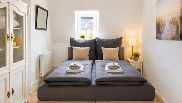 Un lit double avec deux oreillers, une table de chevet avec une lampe, une fenêtre donnant sur un beau paysage et une armoire avec des portes en verre.