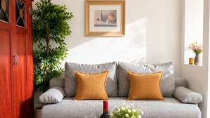 Un salon avec un canapé gris, une table basse en bois, une bouteille de vin et une plante en pot.