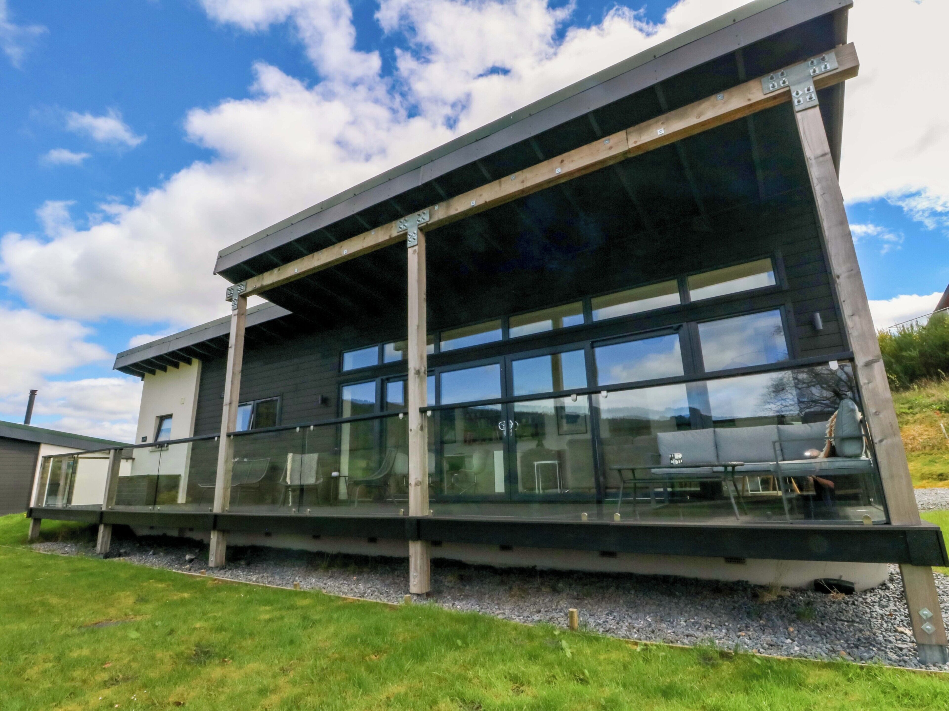Un bâtiment moderne doté de grandes fenêtres, d’un toit plat et d’une allée gravillonnée.
