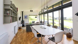 Una cocina moderna con una mesa y sillas blancas, una estantería empotrada y un amplio ventanal con vistas al exterior.