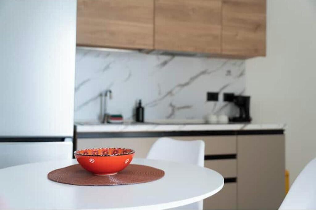 A modern kitchen with a marble backsplash, wooden cabinets, and a white countertop.