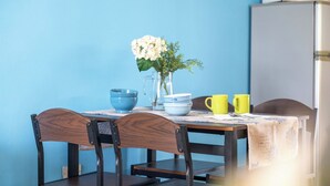 Una mesa de comedor con sillas, un florero con flores y electrodomésticos de cocina.