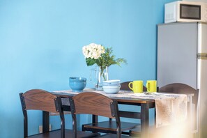 Ein Esstisch mit Stühlen, eine Vase mit Blumen und Küchengeräten.