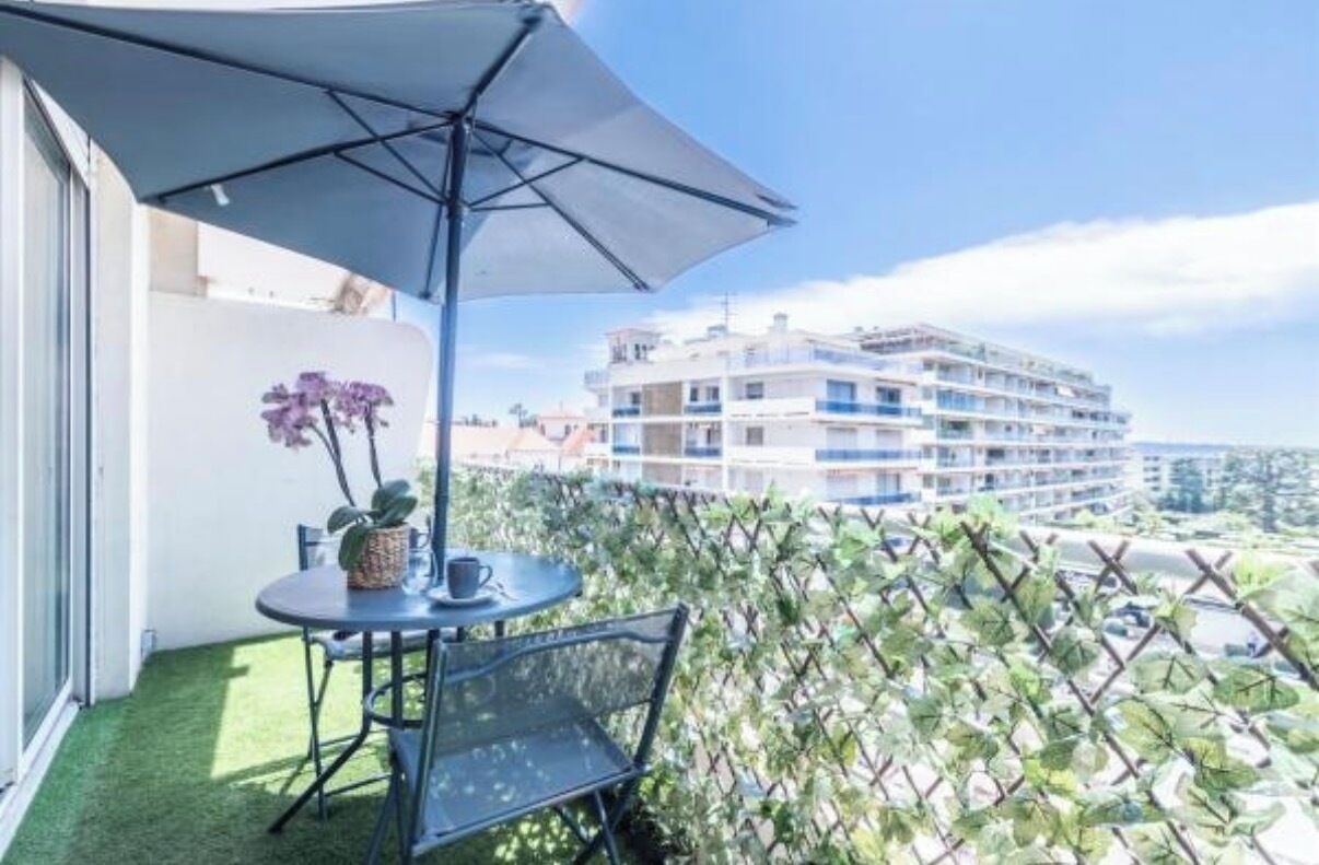 A balcony with a table, chairs, an umbrella, and a potted plant.