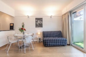 A modern living room with a round dining table, metal chairs, a sofa, a small side table with a lamp, and a framed picture on the wall. - Apartment on the Croisette in Cannes (Cannes)