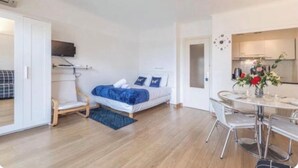 Un dormitori modern amb llit, taula de nit i una petita zona de seients.