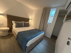 A bedroom with a bed, bedside table, and a window with curtains. - Oporto Riverside Apartments (Porto)