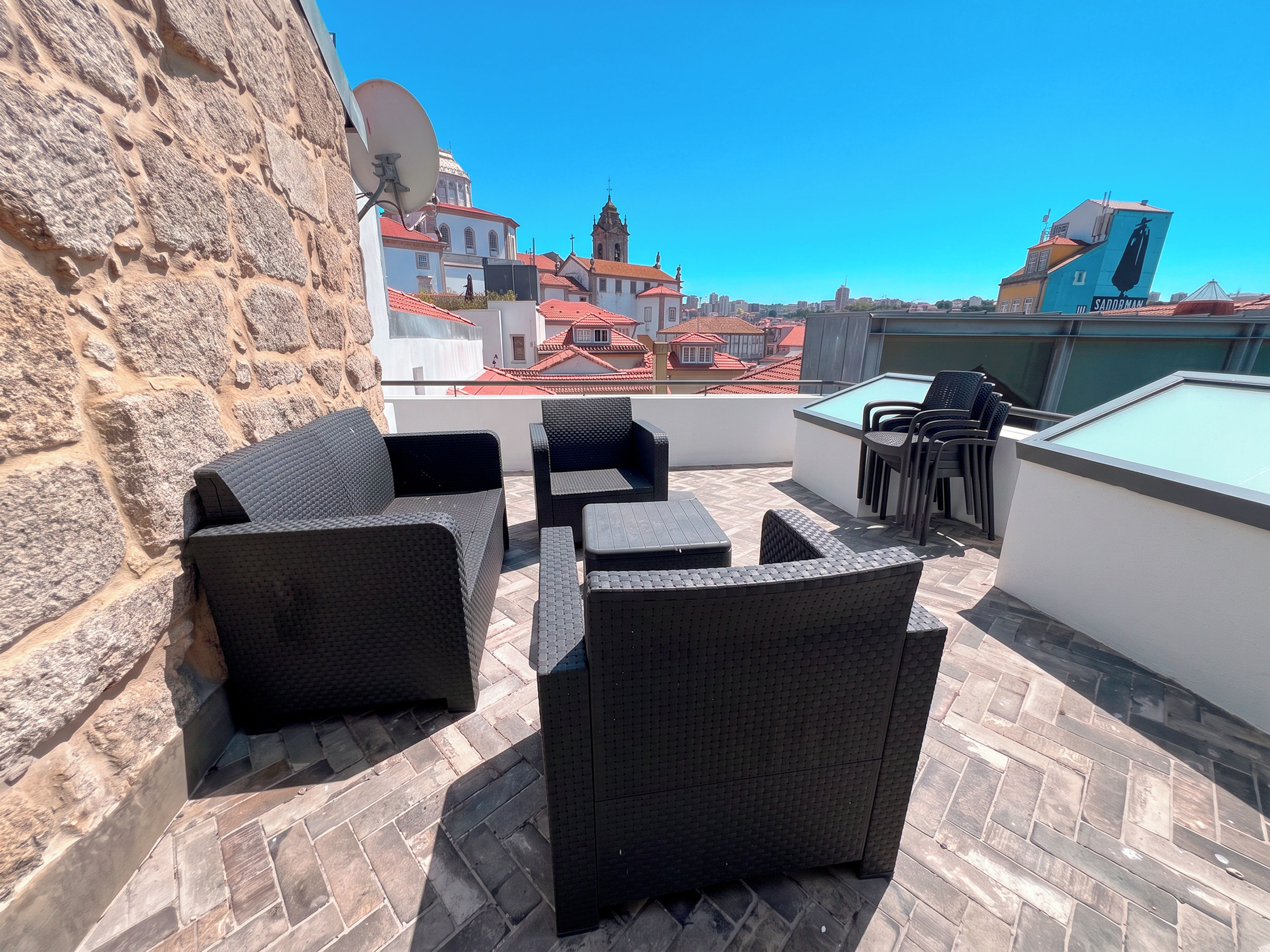 Una terraza en la azotea con mobiliario de mimbre, una mesa de billar y vistas a edificios históricos.