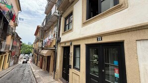 A narrow cobblestone street lined with multi-story buildings, some with balconies and air conditioning units. - Oporto Riverside Apartments (Porto)