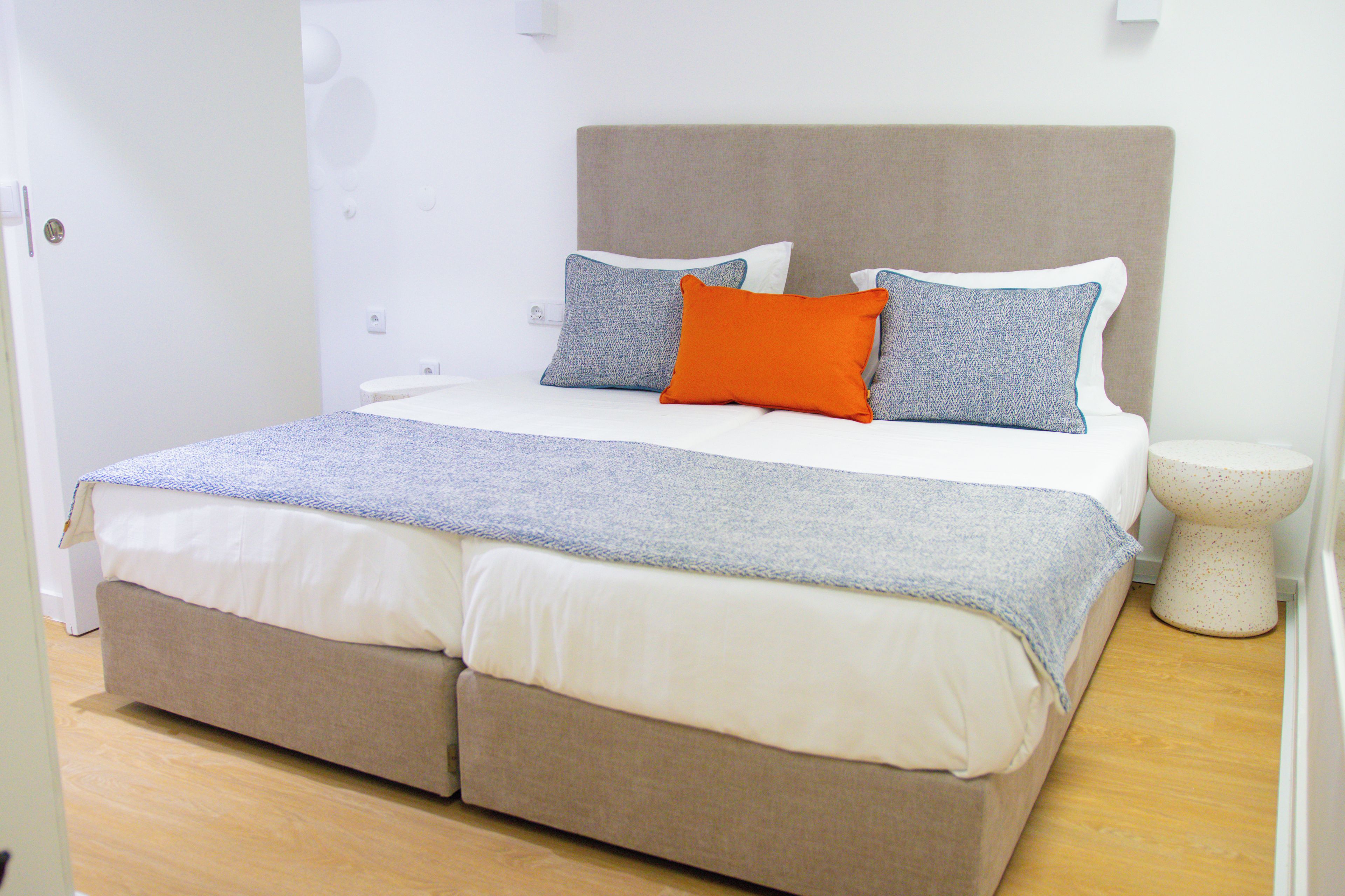 A bed with a headboard, two pillows, a blanket, and a bedside table with a lamp.