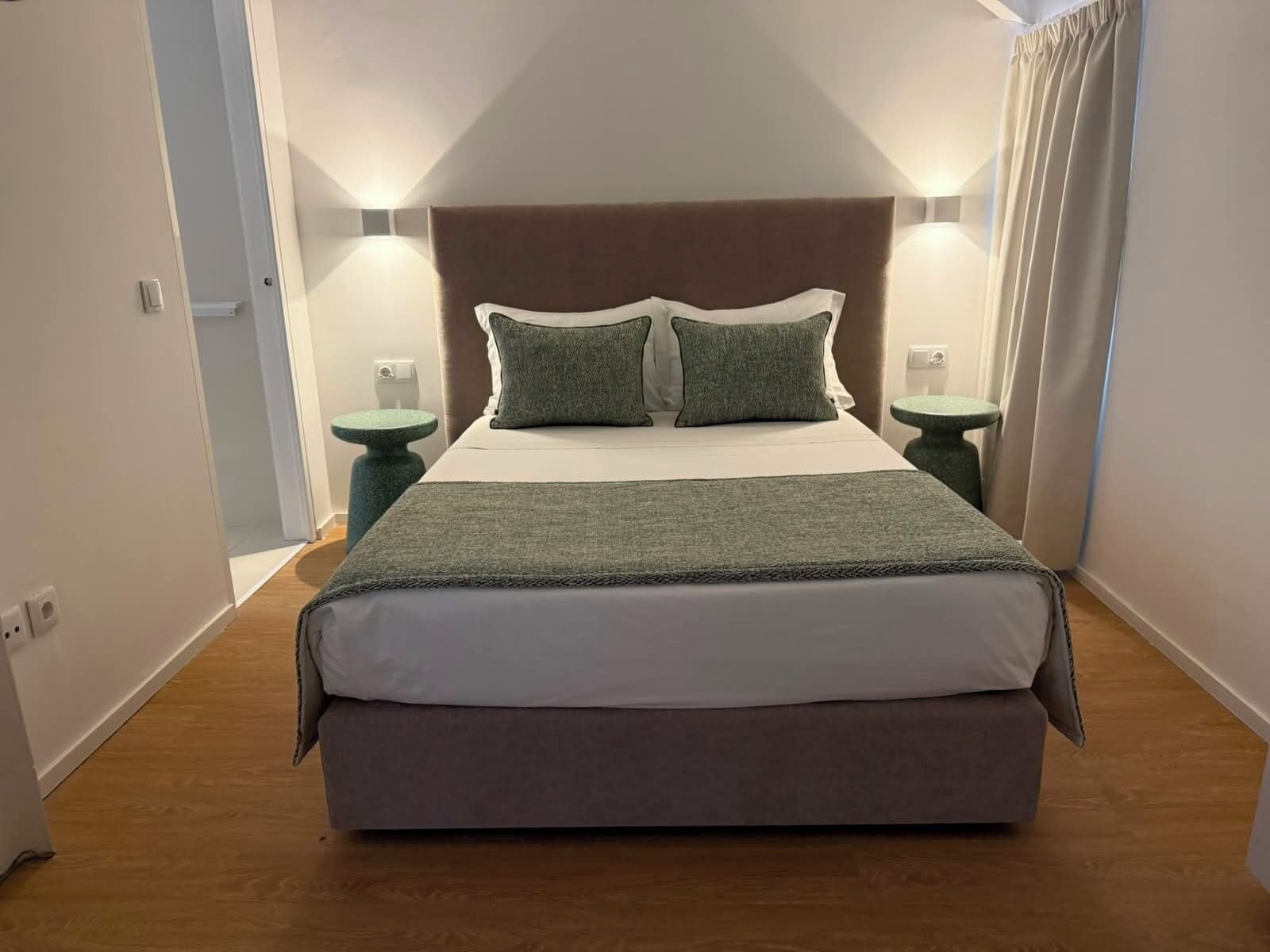 A bedroom with a bed, two bedside tables, and a headboard.