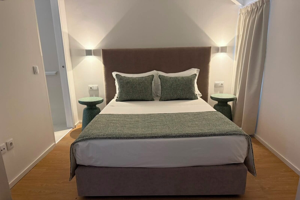 Ein Schlafzimmer mit einem Bett, zwei Nachttischen und einem Kopfteil.