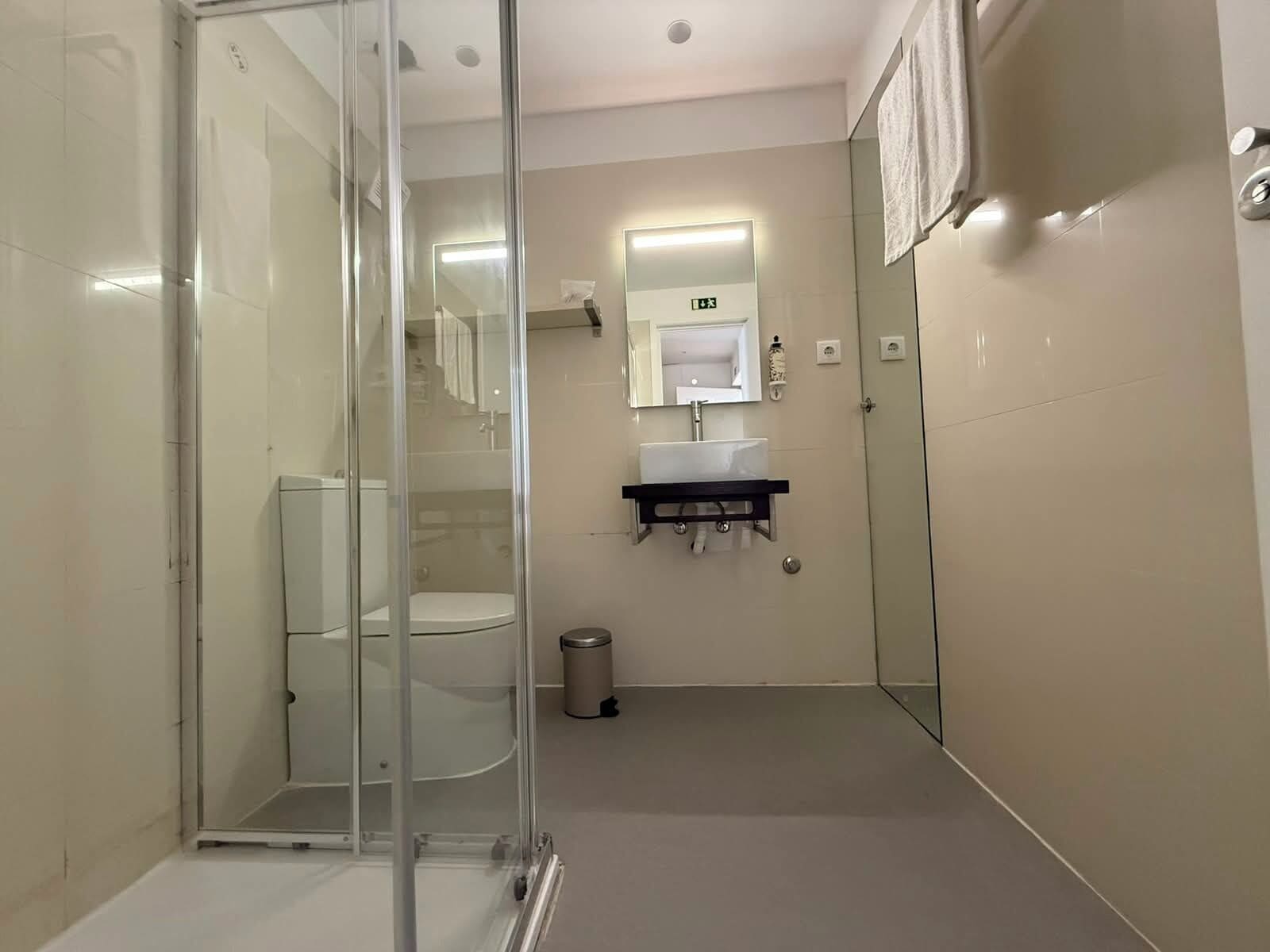 A modern bathroom with a glass-enclosed shower, a sink with a mirror, and a toilet.