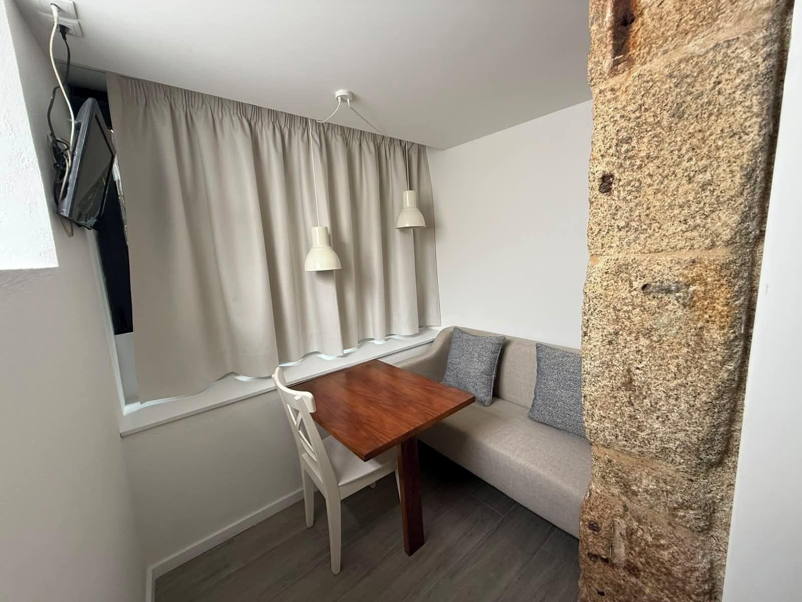 Un espacio habitable compacto con una mesa de comedor, un sofá y dos lámparas colgantes.