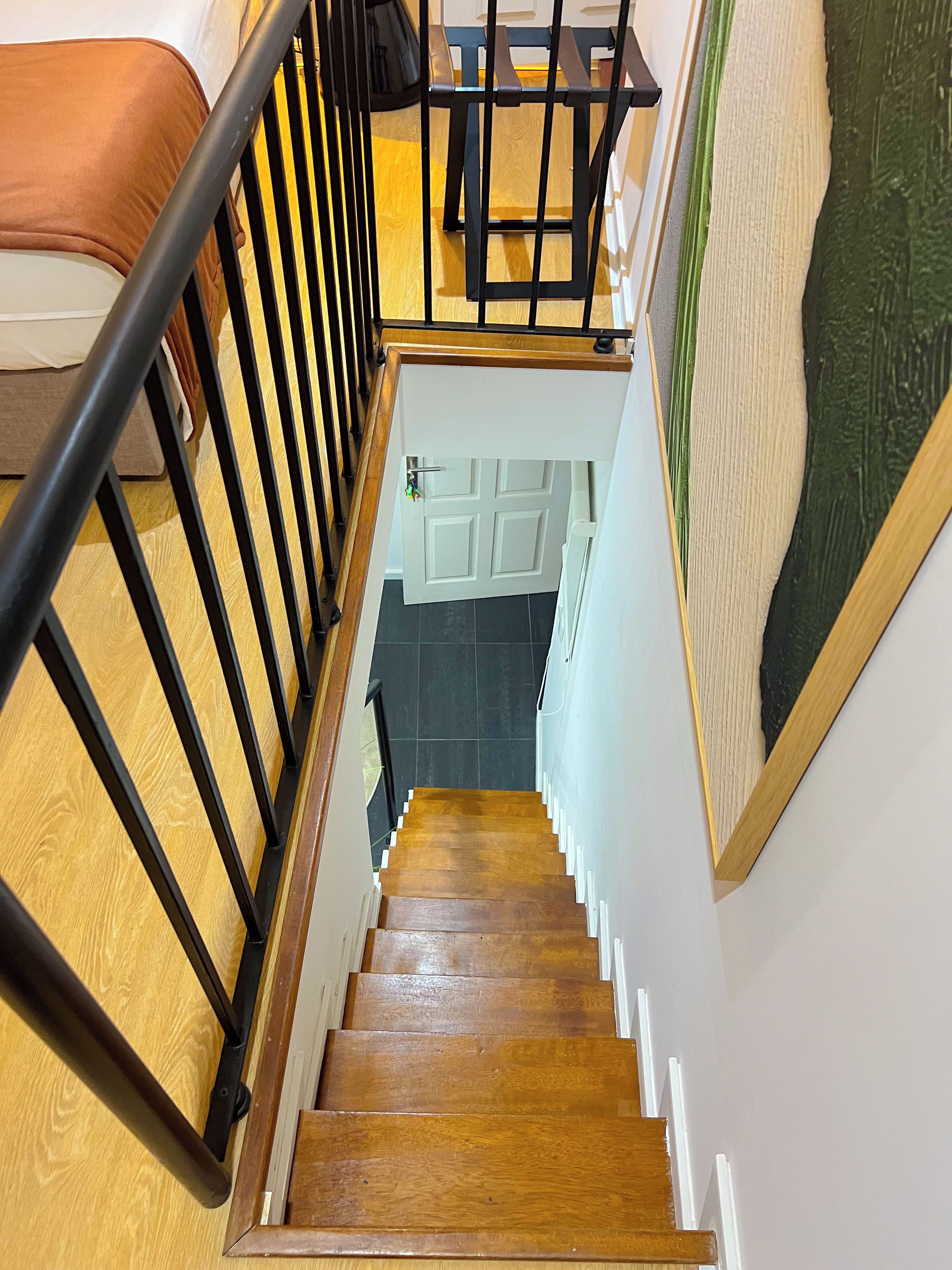 A wooden staircase with a black metal railing leading to a landing.