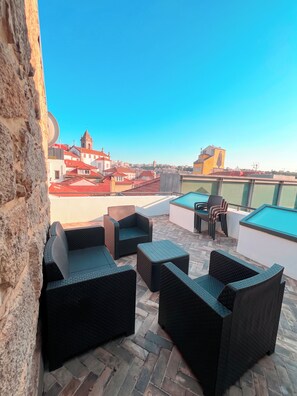 A rooftop terrace with wicker furniture, a pool table, and a view of a cityscape including a church. - Oporto Riverside Apartments (Porto)