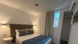 A bedroom with a bed, bedside table, and a window with curtains. - Oporto Riverside Apartments (Porto)