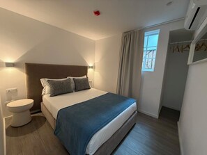 Ein Schlafzimmer mit Bett, Nachttisch und einem Fenster mit Vorhängen.