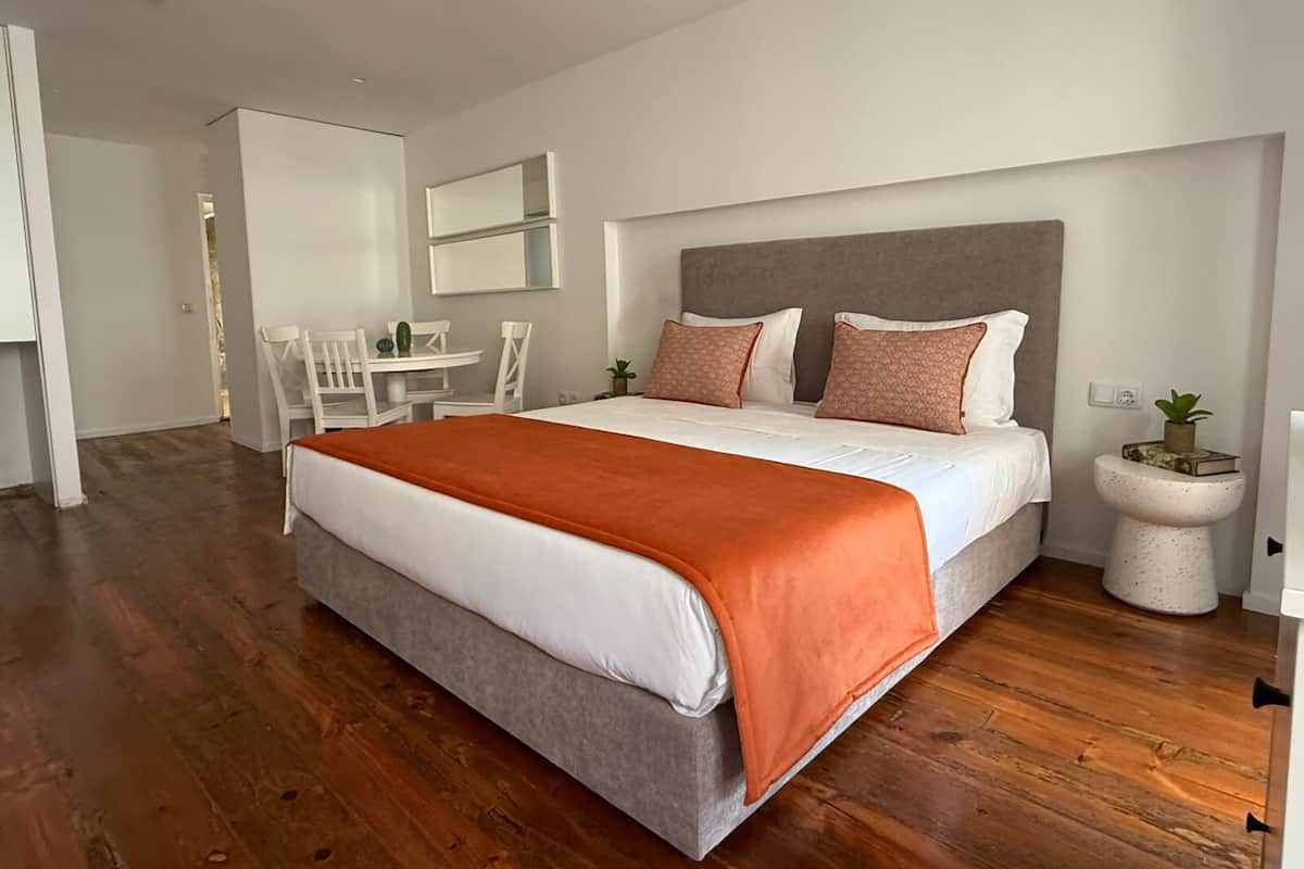 A modern bedroom with a large bed, a desk, and a chair.