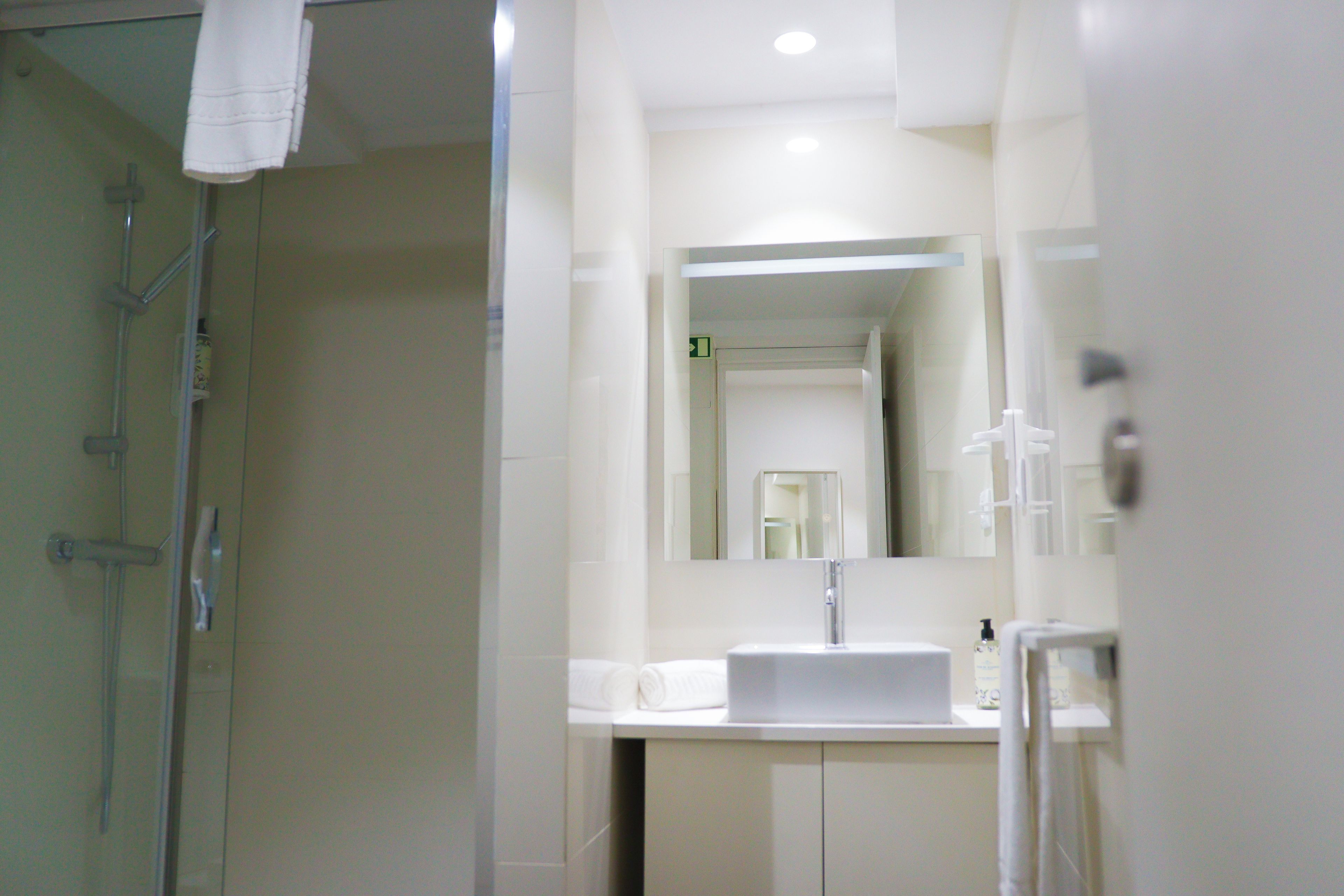 Ein Badezimmer mit Dusche, Waschbecken und Spiegel.