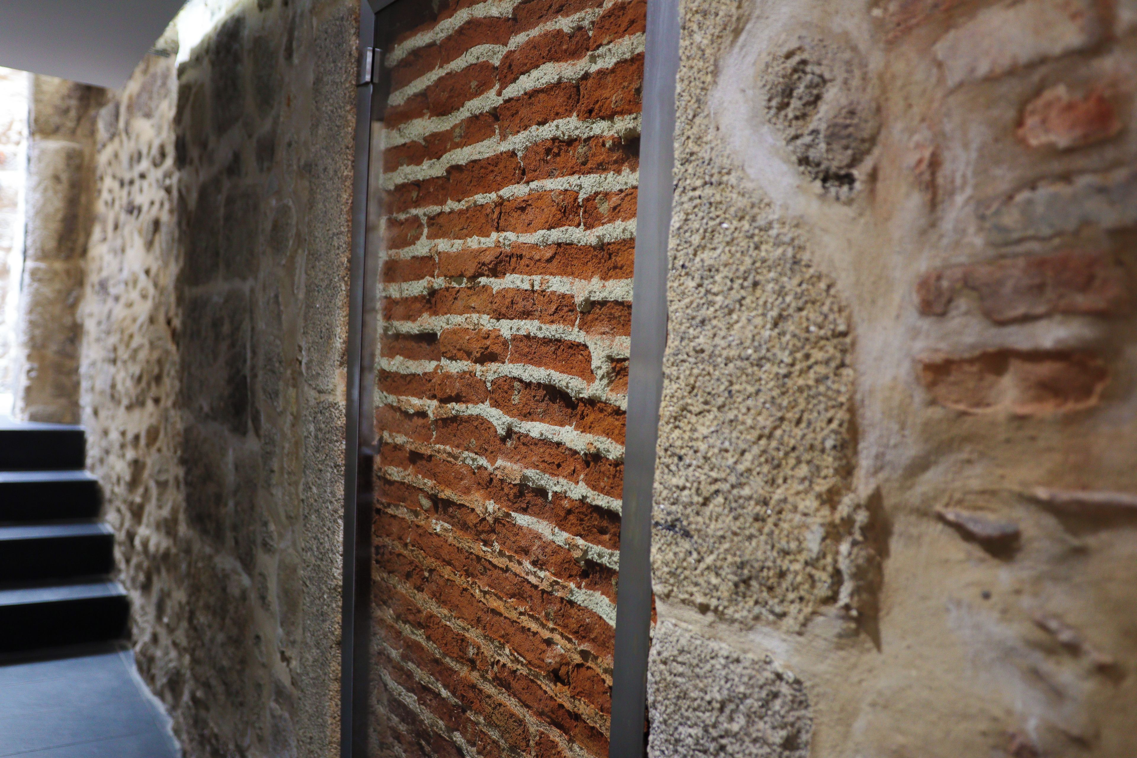 A brick wall with a vertical metal beam.